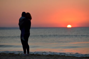 Anne ve oğlu sahilde günbatımı zaman ayakta. Sağlıklı