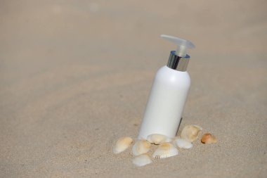 Tüp güneş koruma kum plajı üzerinde kabukları ile birlikte