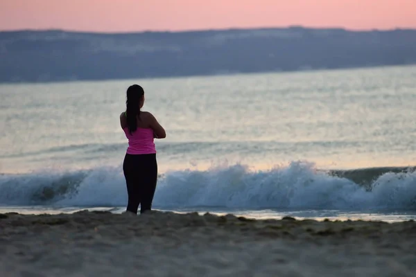 Hermosa joven mujer disfruta de la salida del sol de la mañana en una playa, ella — Foto de Stock