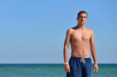 Young man with athletic body in blue shorts standing with his ba