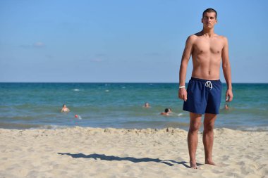 Young man with athletic body in blue shorts standing with his ba