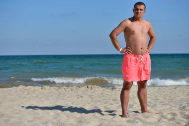 Young man with athletic body in pink shorts standing with his ba