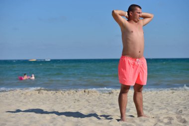 Young man with athletic body in pink shorts standing with his ba