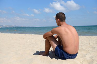 Young man with athletic body in blue shorts standing with the ba