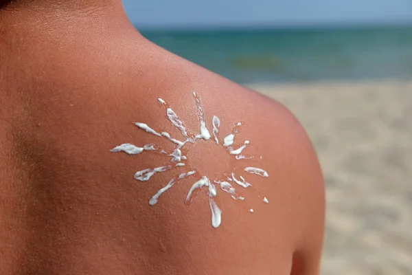Acercamiento del sol dibujado con crema solar en el hombro de un joven — Foto de Stock