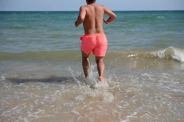 Young man is running in the water of the Black Sea, ready to hav — 图库照片