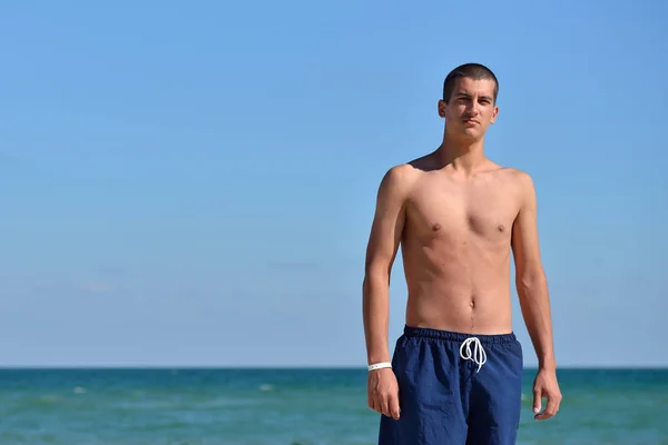 Young man with athletic body in blue shorts standing with his ba — 图库照片