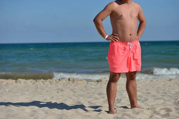 Young man with athletic body in pink shorts standing with his ba — 图库照片