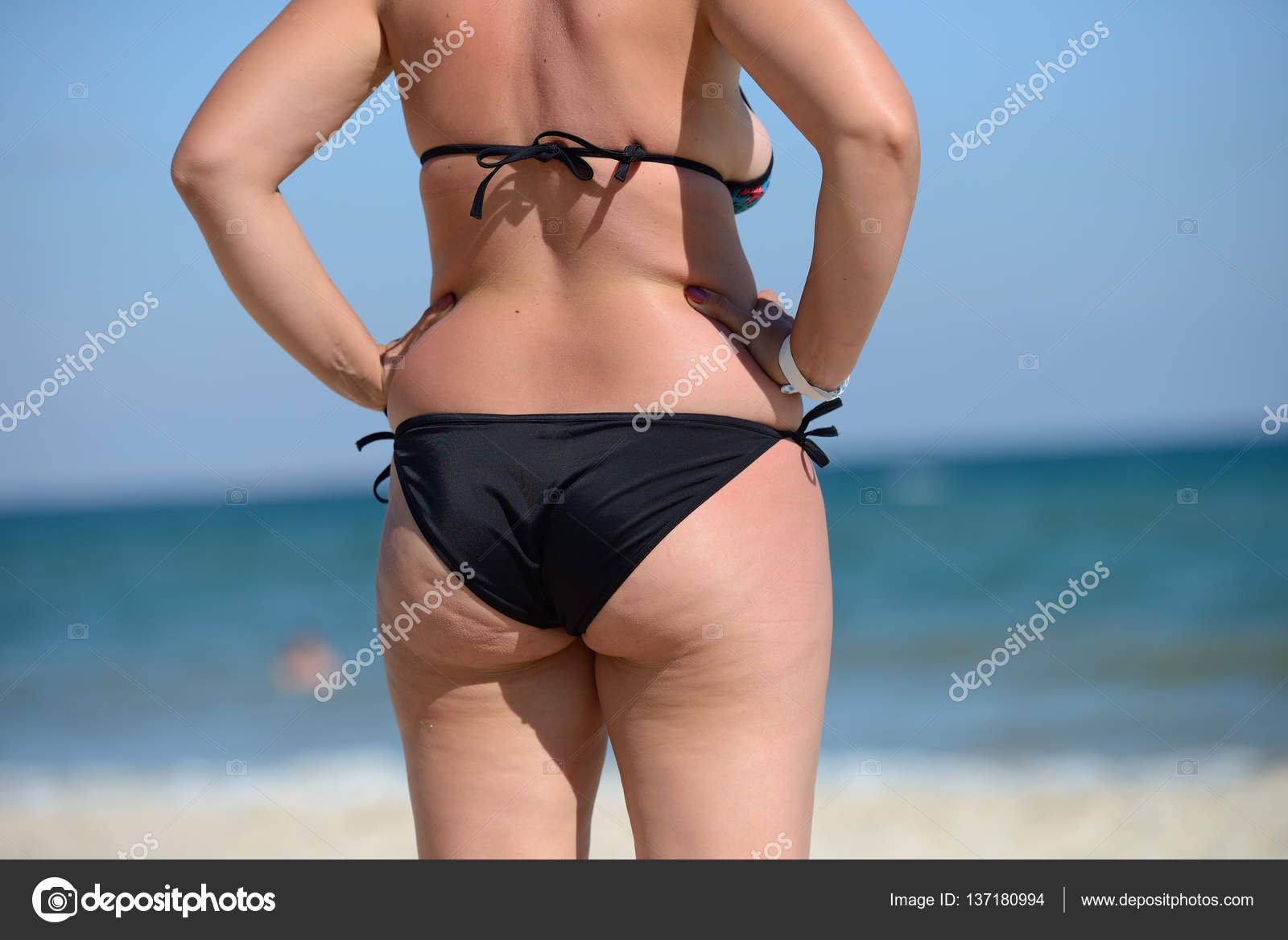 Избыточный вес молодой женщины в купальнике у моря, глядя на 