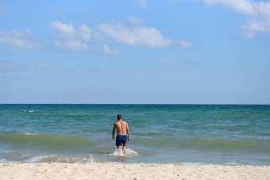Young man in the summer vacation, enjoying the sea waves under t