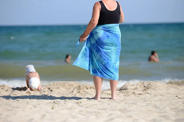 An elegant senior woman in a black swimming costume, with a blue — Stock Photo, Image