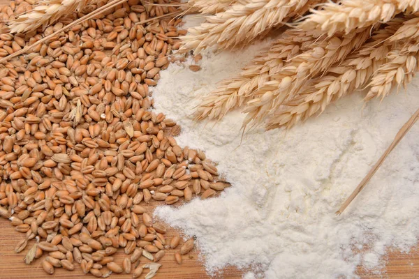 Зерна, колосья пшеницы и мука на деревянном столе. Концепция макина — стоковое фото