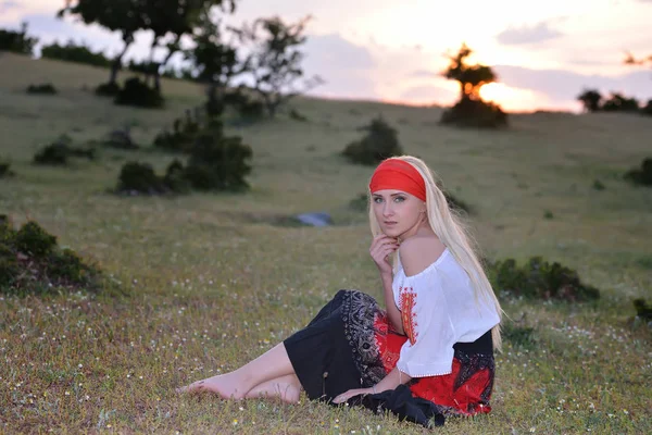 Mooie blonde vrouw op veld bij zonsondergang, zomeravond — Stockfoto