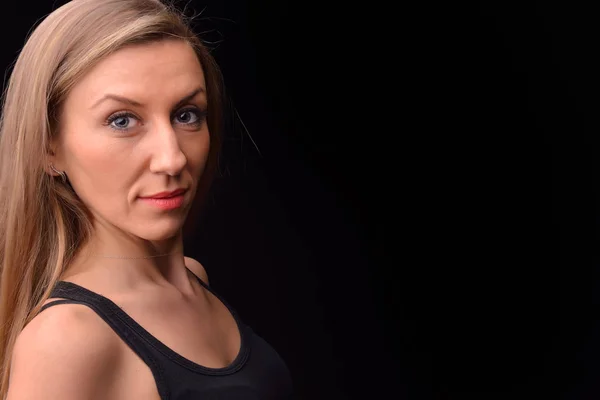 Beautiful blonde young woman in a black undershirt posing in a s — Stock Photo, Image