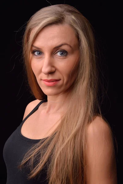 Beautiful blonde young woman in a black undershirt posing in a s — Stock Photo, Image