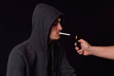 Genç bir çiğ ağzına tutarak siyah kapüşonlu sweatshirt