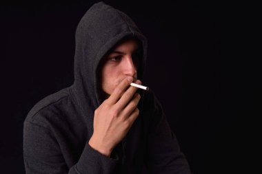 Genç bir sigara bir d siyah kapüşonlu sweatshirt