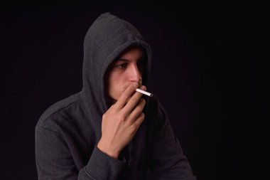Genç bir sigara bir d siyah kapüşonlu sweatshirt