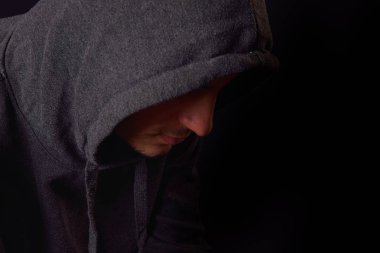 Kendinden emin ve ciddi bir genç adam bir siyah siyah kapüşonlu 