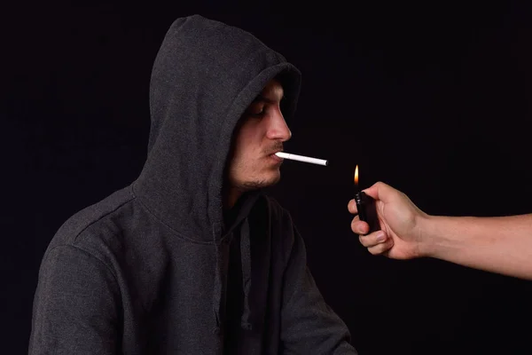 Adolescente em uma camisola com capuz preto segurando em sua boca um cigarro — Fotografia de Stock