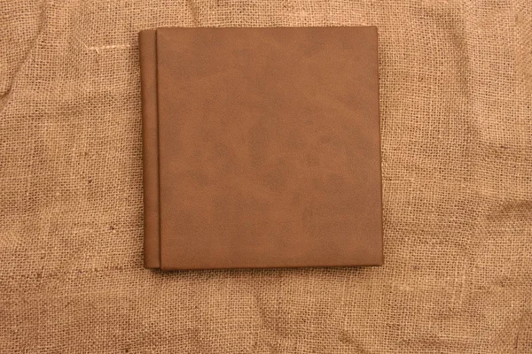 Picture of brown leather photo album cover on jute background. K — Stock Photo, Image