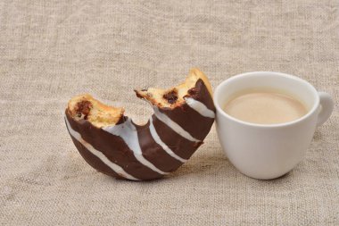 Yarısı dolu çikolata çörek ve fincan kapuçino jüt üzerinde bac