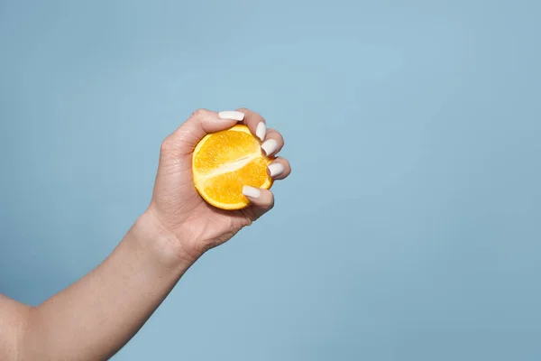 Halv apelsiner i händerna på blå bakgrund, citrus objekt — Stockfoto