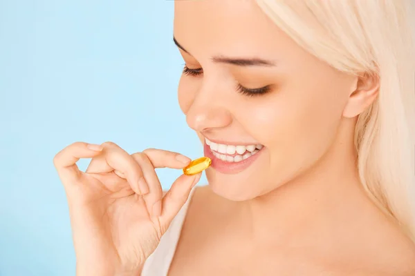 Hermosa chica tomando medicinas, vitaminas, pastillas. Fondo azul — Foto de Stock