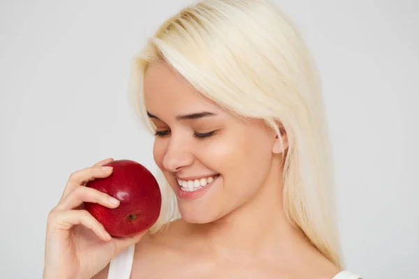 Kvinna med äpple. Vacker flicka med vitt leende på en grå bakgrund, friska tänder. Högupplöst bild — Stockfoto