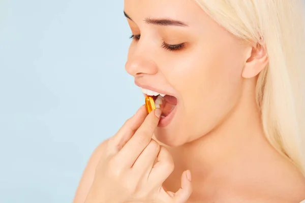 Hermosa chica tomando medicamentos, vitaminas, pastillas.Fondo azul — Foto de Stock