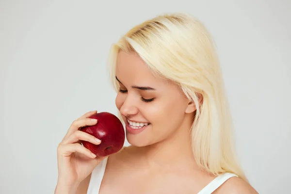 Kvinna med äpple. Vacker flicka med vitt leende på en grå bakgrund, friska tänder. Högupplöst bild — Stockfoto