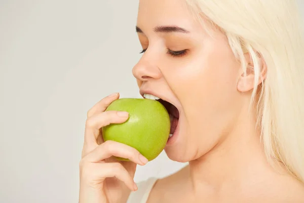 Kobieta z jabłkiem. Piękna dziewczyna z bliska jedząca jabłko na szarym tle, zdrowe zęby. Obraz wysokiej rozdzielczości — Zdjęcie stockowe