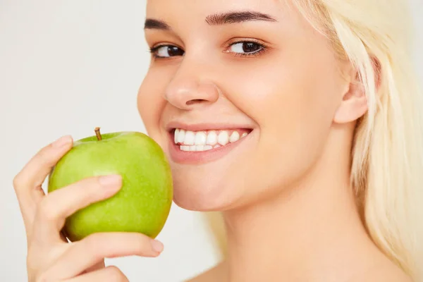 Kvinna med äpple. Vacker flicka närbild med vitt leende på en grå bakgrund, friska tänder. Högupplöst bild — Stockfoto