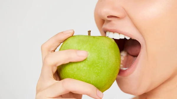 Elmalı Kadın. Gri arka planda elma yiyen güzel bir kız, sağlıklı dişler. Yüksek Çözünürlüklü Resim — Stok fotoğraf