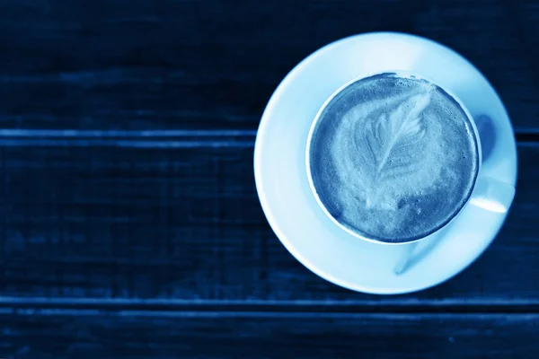 Colore dell'anno, 2020. Tazza di cappuccino o latte su fondo legno, tonica classica foto blu. tazza di caffè, vista dall'alto . — Foto Stock