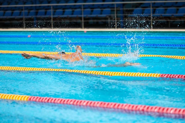 在碧水清澈的游泳池里，一个运动员以蝴蝶的形式游泳. — 图库照片