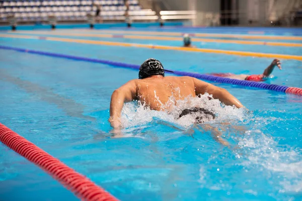 Atletisk man simmar i fjäril stil i poolen med klarblått vatten. — Stockfoto