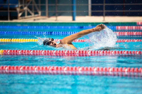 Atletický muž plavání v přední crawl stylu v bazénu s průzračnou modrou vodou. — Stock fotografie