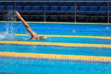 Yüzme havuzunda temiz mavi suyla yüzen atletik bir adam..