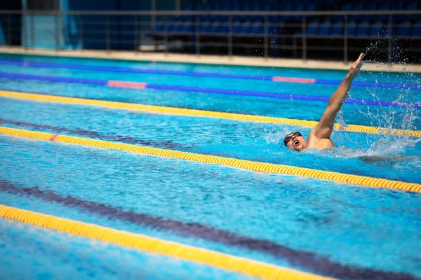 Atletický muž plavání v přední crawl stylu v bazénu s průzračnou modrou vodou. — Stock fotografie