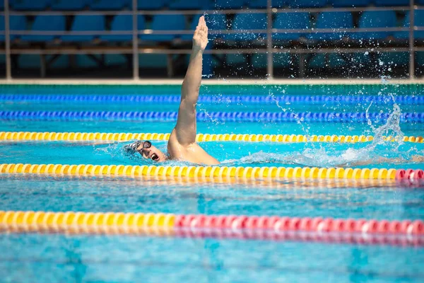 Atletický muž plavání v přední crawl stylu v bazénu s průzračnou modrou vodou. — Stock fotografie