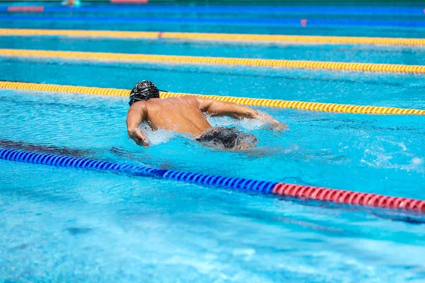 Atletisk man simmar i fjäril stil i poolen med klarblått vatten. — Stockfoto