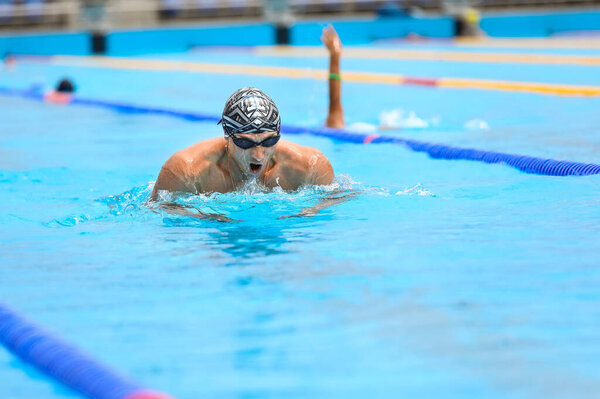Атлетик плавает в стиле брасса в бассейне
.