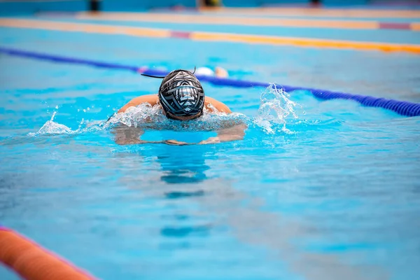 Athletic man swimming in Breaststroke style in the swimming pool.