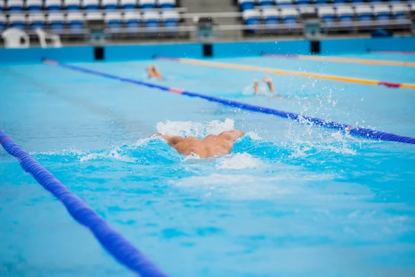 Atletisk man simmar i fjäril stil i poolen med klarblått vatten. — Stockfoto