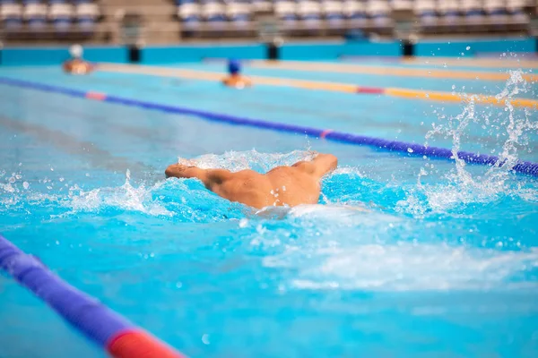 Atletisk man simmar i fjäril stil i poolen med klarblått vatten. — Stockfoto