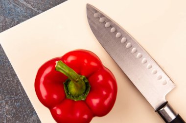 Kesici bir bıçakla suni taştan yapılmış bir kesme tahtasına biber parçası.