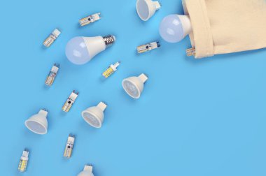 .Mavi arka planda birkaç tane ampul var. Enerji tasarrufu kavramı. Ftat yatıyordu, üst görünüm, kopyalama alanı. Tavan lambaları için ampuller.