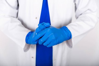 Bakterilere karşı antiseptik içeren mavi lastik eldiven tedavisi. Doktor mavi eldivenli bir antiseptik kullanır. Beyaz önlüklü ve koruyucu eldivenli bir doktor. Eldivenli dezenfektan kullanımı.
