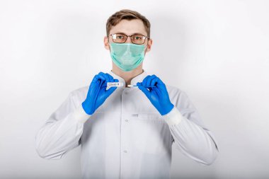 Bir sağlık uzmanı COVID-19 lekesi alır. Beyaz bir bornoz giy, koruyucu bir maskeden yapılmış eldivenler giy. Analiz için test tüpü. Analiz ve enfeksiyon örneği için test tüpü olan bir doktor..